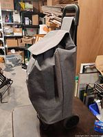 Side view of the large capacity grocery buggy showing grey woven fabric, black handle, and wheels.