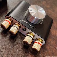 Top view showing the large silver volume knob and Nobsound branding on black metal case with speaker terminals.