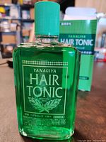 Front view of the green transparent bottle labeled Yanagiya Hair Tonic with green screw cap.