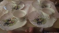 Four ceramic snack sets with cups and plates in floral design and gold trim.