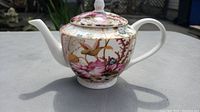 Side view of Maxwell Williams Cashmere pattern teapot showing the floral and bird design with spout and handle.