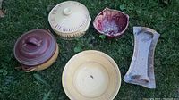 Five pieces of local pottery arranged on grass: two casseroles with lids, salad bowl, strainer bowl, and sandwich plate.