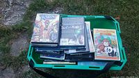 Green bin filled with assorted DVDs including Curious George