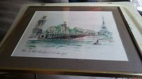 Framed watercolor painting on a table showing Paris street scene with bridge and Eiffel Tower