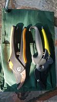Photo showing two hand pruners placed on top of a green fabric carrying case with pockets