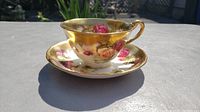 Side view of Royal Chelsea Golden Rose teacup on matching saucer showing floral rose design and gold trim.