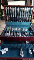 Full view of the flatware set inside the open presentation box showing the arrangement of knives, forks, and spoons.