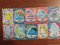Full set of all 10 Topps Pokemon cards arranged in two rows on a wooden surface showing front artwork and numbering.