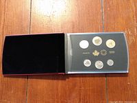 Open black velvet case with six specimen coins in protective transparent case showing front faces.