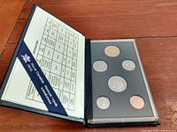 Opened black protective case showing a set of six coins dated 1994 including different sizes laid out in inserts with catalog information.