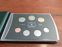 Open view of the coin set inside the folder showing seven Canadian coins arranged in two rows: $2, $1, 50c on top, 25c, 10c, 5c, 1c on bottom with a Royal Canadian Mint identification plaque in the center.