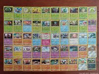 Photo showing the front side of 50 unique Pokemon cards laid out in rows on a wooden surface. Cards are from 2019 with various Pokemon types shown.