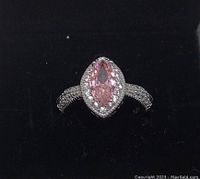 Front view of the sterling silver ring with marquise-cut pink topaz center stone surrounded by white topaz stones on the band.