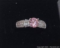 Front view of sterling silver ring with round pink topaz center stone and white topaz accents on band.