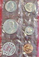 Front view of sealed coin set showing Lincoln penny, Roosevelt dime, Kennedy half dollar, and Buffalo Mint seal.