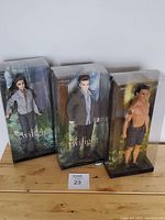 Three dolls in original packaging, Bella, Edward, and Jacob from Twilight collection, arranged side by side.