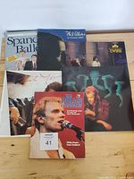 Collection of 7 1980s concert programs and books featuring various artists including Spain Ballet, Phil Collins, The Twins, Paul Young, and Sting.