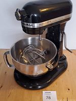 Front-quarter view of mixer with bowl attached and wire whisk inside