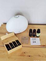 White Saje ultrasonic diffuser with essential oils displayed on wooden surface