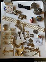 Photo of the entire collection showing brooches, pins, bracelets, belt, bow tie, and decorative boxes arranged on a white surface.