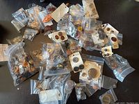 Overview of vintage buttons all in neutral colors in various small plastic bags and some attached to cards on a dark surface.