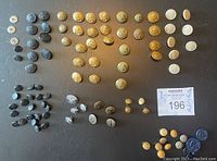 Overview of assortment of vintage military and police buttons arranged on black surface, differing in size, color, and insignia