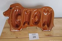 Front view of brown ceramic dachshund-shaped snack tray spelling out 'CHOW'