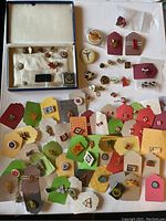Top-down view of a large assortment of vintage pins with colorful tags and small boxes