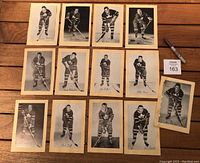 Top-down view of all 13 hockey photos laid out on wooden table, showing individual players in black and white poses wearing Toronto Maple Leafs jerseys.