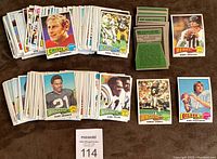 Two stacks of vintage 1975 Topps football cards with several cards laid out featuring NFL players from multiple teams. Brightly colored fronts with player images and team logos. Cards appear sharp and well-preserved.