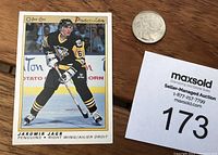 Front view of the hockey card showing Jaromir Jagr in Pittsburgh Penguins uniform with number 68, along with a silver coin and auction lot number card for scale.