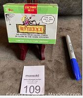 Front of box showing title, contents, and factory seal next to a pen for scale.