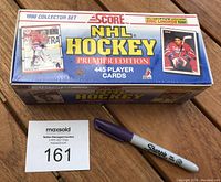 Factory sealed box of 1990 Score NHL Hockey Premier Edition set on wooden surface with auction tag and Sharpie marker.