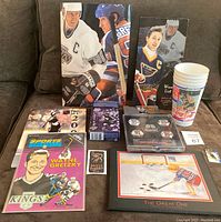 All 11 items displayed on a couch including menus, laminated card, pin set in case, business card, comic, Kraft box, plastic cups and small pin