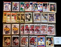 Photo of various hockey rookie cards laid out in rows, featuring players in their team jerseys, in protective plastic sleeves