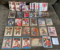Photo showing a large array of 47 Patrick Roy hockey cards from various years and sets arranged on a surface, featuring different card designs, colors and styles.