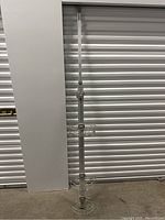 Full vertical view of the adjustable shower rack showing the three wire baskets and mounting pole.