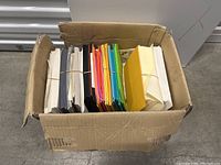 Top view showing multiple stacks of cardstock paper in a cardboard box with different colors.