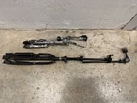 Metal tripod drum stand with attached adjustable arms and clamps on concrete floor