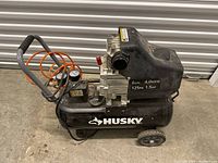 Side-angle view of Husky air compressor showing tank, gauges, and handle.