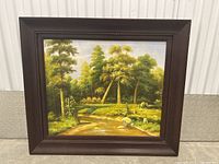 Frontal view of the large oil on canvas painting showing a peaceful wooded landscape with creek and rocks inside a dark wooden frame.