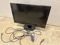 Digital photo of Dell LED monitor with stand and VGA cable on floor, screen off, showing front view.