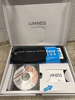 White Luminess Air box open showing black carrying case, blue and white guide, DVD, and makeup kit box inside