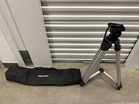 Neewer tripod folded and laboring standing next to matching black carrying bag with Neewer branding