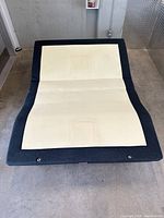 Frame laid flat showing fabric upholstery and hinge sections