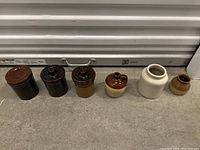 Wide view of all six stoneware jars side by side showing size and color variation