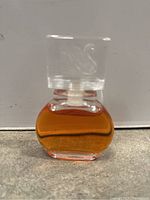 Front view of vintage Vanderbilt perfume bottle showing amber liquid inside clear glass bottle with clear cap embossed with swan design.