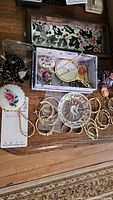 Wide view of various jewelry and accessories on wood surface showing earrings, hand mirrors, crystal holder and other items