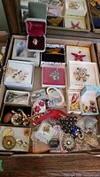Photo showing assorted costume jewelry pins and brooches displayed on a surface, some in original boxes.