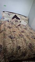 Queen size bed with floral king size bedding placed against a plain white wall, showing comforter and pillows